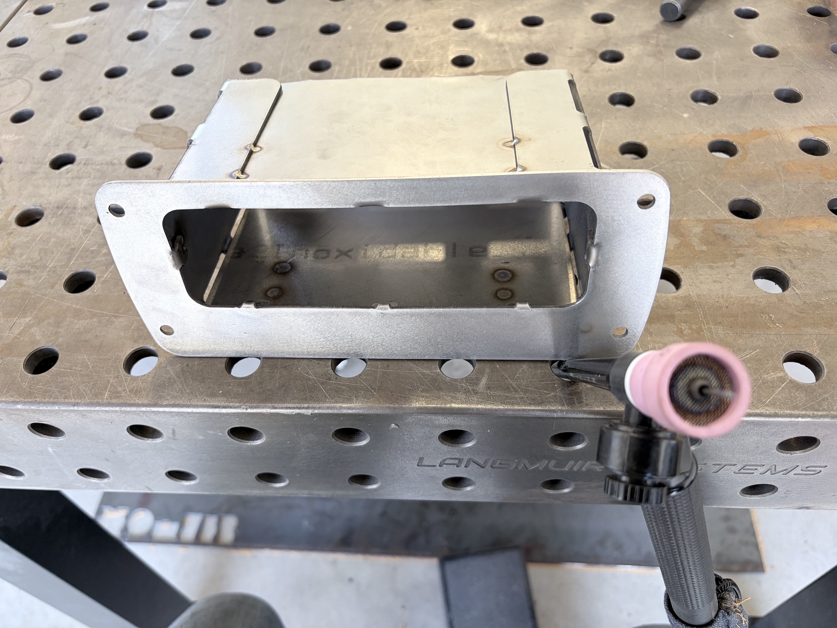 Welded stainless steel boat console compartment with a flanged opening.