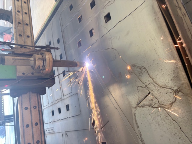 CNC plasma cutter cutting mild steel sheet on a fabrication table.