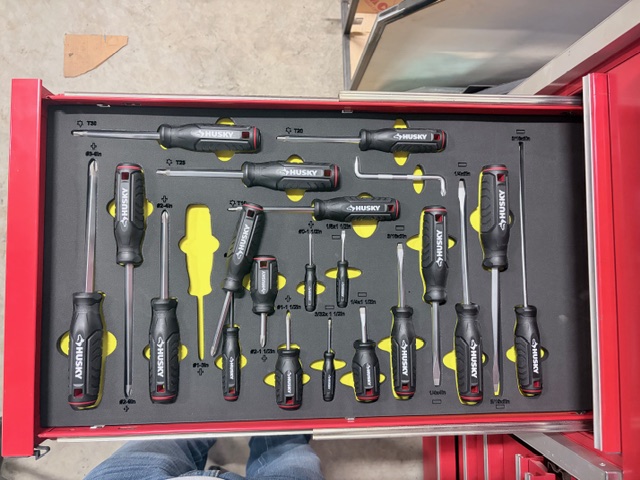 Custom screwdriver drawer organization panel with labeled cutouts inside a red tool chest drawer.